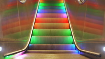 Pedestrian crossing escalator with multi-colored LED rainbow lights moving down endlessly without people. Automatic stairs at Stockholm subway.