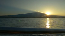 The sunrise over a mountain from a boat on the ocean