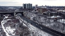 Aerial drone view of Prince Edward Viaduct in dynamic downtown Toronto on a cold winter day. Aircraft is placed right above Don Valley Parkway showing moderate traffic. Panning shot to the right.