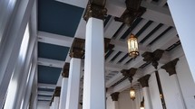 Panning through columns inside of a bank or church facing up towards the ceiling.