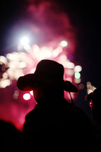 silhouette of a child in a cowboy hat watching fireworks 