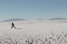 a boy running on sand dunes 