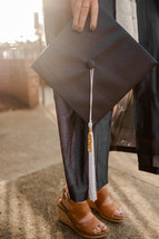 female graduate holding a graduation cap 