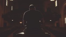 Silhouette of the back of a man sitting on a stage in an empty auditorium.