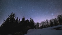 Astronomy time-lapse Starry night sky and stars above wooden hut in wilderness forest nature
