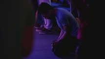 a man kneeling on the floor during a worship service 