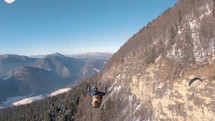 Flying on paraglide by rocky alpine mountains forest nature.

