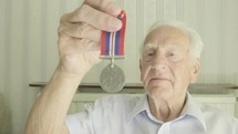 Senior caucasian man looking at an old medal themes of retired memories respect honour
