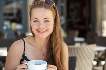 a smiling woman holding a coffee cup in the city 