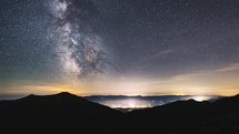 Starry night sky in mountains Time lapse with Milky way galaxy stars motion fast over countryside traffic. Night to day Astronomy
