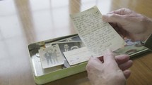 elderly caucasian man looking at old photographs and love notes in a memory box