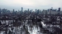 Drone view of Riverdale Park West in dynamic Toronto on a winter day. Drone approaching downtown while flying over leafless trees. Panoramic scenario of urban cityscape with a calm and cold feel.