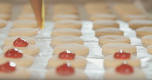 Baker preparing butter cookies with strawberry jam and powdered sugar