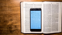 cellphone with Bible app and open Bibles 