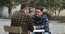Two men talking on a cafe patio