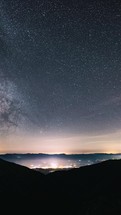 Vertical Timelapse of milky way galaxy stars in night sky over countryside traffic astronomy landscape
