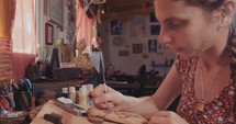 Artist painting and decorating a wooden Buddhist prayer wheel.