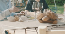 Slow motion tracking shot of a group of people eating and drinking wine at an outdoor table.
