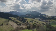 Aerial flight over spring landscape with clouds moving over mountains time lapse
