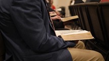 people sitting in pews with Bible's in their laps during a worship service 