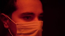 man standing in red light wearing a surgical mask 