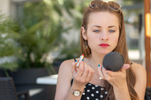 a woman putting on makeup outdoors 