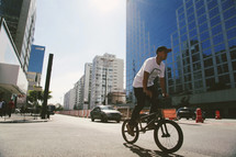 young man pedaling a bicycle on a city street 