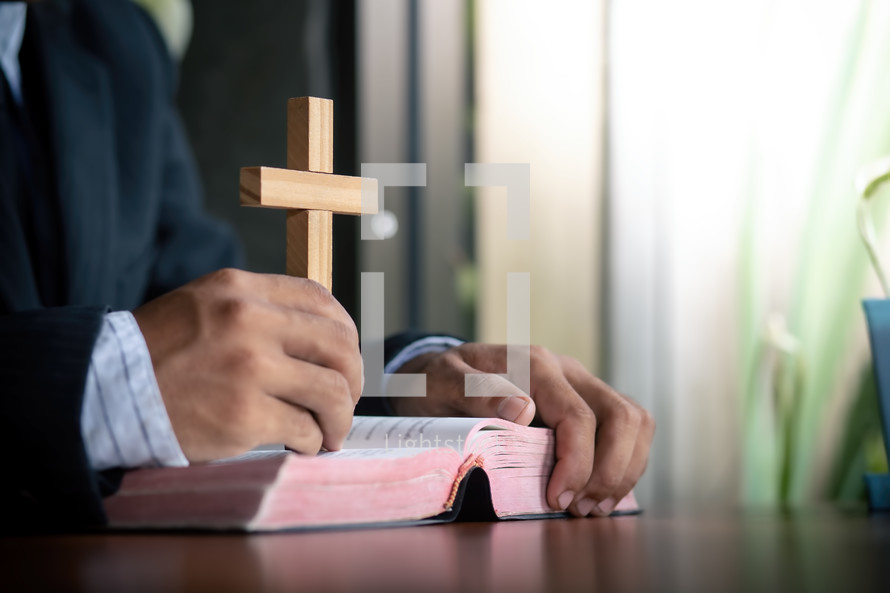 a man holding a wood cross over a Bible 