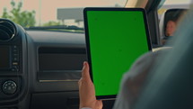 woman sitting at the passenger seat tapping on isolated green screen summer road trip