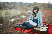 plaid blanket, blanket, reading, woman, sitting, outdoors, guitar 