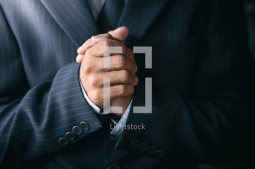 praying hands of a male in a suit 