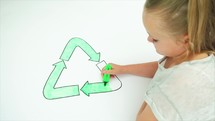 Caucasian girl colouring in an image of the recycle symbol