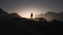 Silhouette of a male hiker on top of a mountain during sunset