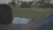 teen girl reading a Bible in a hammock 