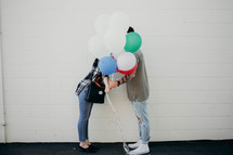 a couple kissing behind balloons 