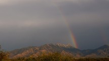 A colorful desert rainbow with scenic mountains