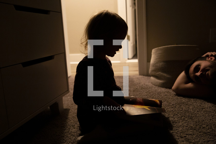 silhoutte of a child reading a book 