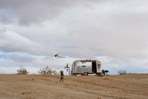 camper in the desert and boy flying a kite 