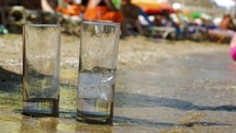 Pouring water into two glasses on beach
