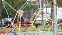 Happy little boy climbing on playground equipment