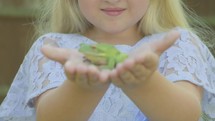 Pre teen caucasian girl holding a white lipped tree frog in her hands which then jumps off themes of imagination fantasy magic stories childhood