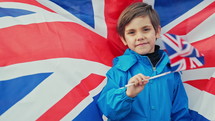 Little child son, british patriot kid waving Union Jack flag outdoors. Symbol of democracy, traveling Great Britain, future celebration, UK banner, Remembrance Day, election. High quality 4k footage