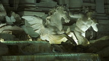 White statues on the Trevi Fountain where water is falling into the water basin at the Piazza di Trevi in Rome. 