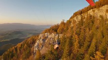 Paragliding above an autumn forest and mountains with rocky cliffs
