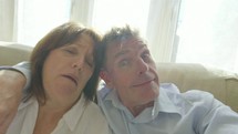 Romantic carefree senior caucasian couple having fun taking selfies on a smart phone in their living room