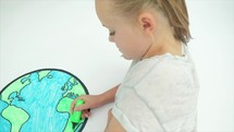 Caucasian girl colouring in an image of the earth