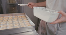 Baker preparing butter cookies with strawberry jam and powdered sugar
