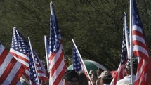 Many American flags being carried in a parade