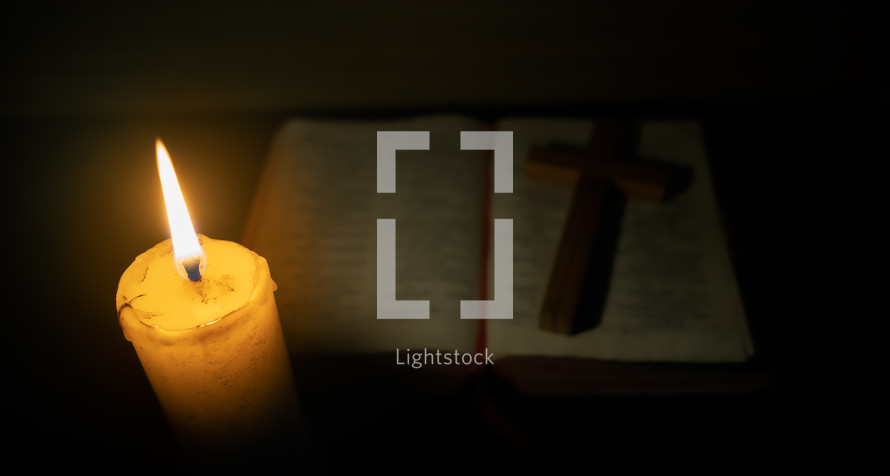 Candle with the Bible on wooden table in the night. worship prayer and bible study concept.