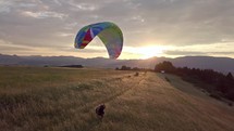 Playing with paraglider in golden meadow at sunset 
